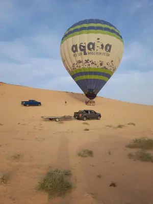a hot air balloon flying over a car in the desert at Rand desert camp in Wadi Rum