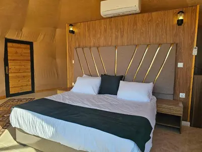 a bedroom with a large bed with a wooden headboard at Rand desert camp in Wadi Rum
