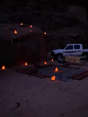 a white truck parked in front of a cave with fires at Bedouin oasis in Wadi Rum