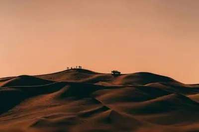 a group of people standing on top of a sand hill at Bedouin oasis in Wadi Rum