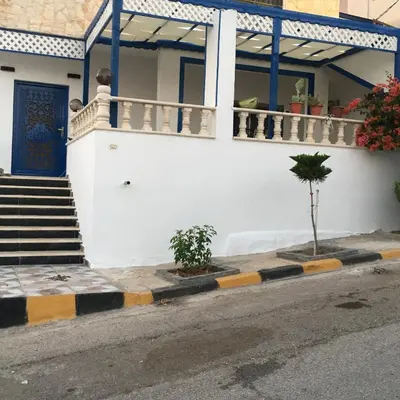 a house with a blue door on a street at بيت العُمري (ام قيس) in Um Qeis