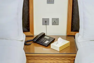 a phone and a box on a table next to a bed at Dweik Hotel LUXURY 3 in Aqaba