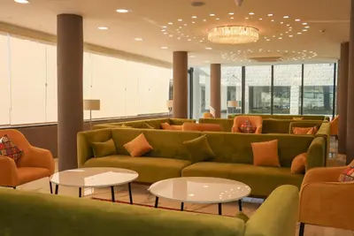 a lobby with green couches and tables and windows at The RN Hotels in Wadi Musa
