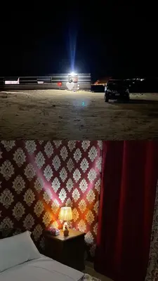 a bed and a car in a parking lot at night at Why not camp in Wadi Rum