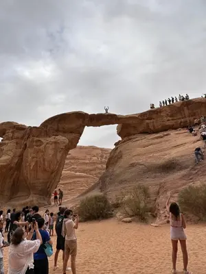 a group of people taking pictures of a rock formation at Wadi Rum Khalifa Camp in Wadi Rum
