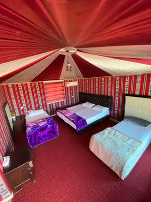 two beds in a room with red curtains at Rum Serena Camp in Wadi Rum