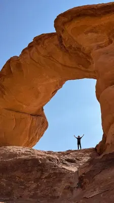 a man standing on top of a rock formation at Wadi rum sand Delight camp in Wadi Rum