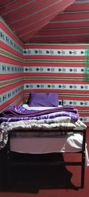 a bed in a room with a wall with writing at Wadi rum sand Delight camp in Wadi Rum