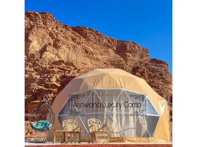 a tent with chairs in front of a mountain at Arjowana Luxury Camp & Bubbles Hotel in Wadi Rum