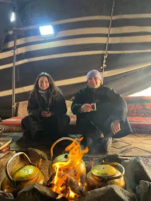a man and woman sitting around a fire at Arjowana Luxury Camp & Bubbles Hotel in Wadi Rum