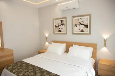 a bedroom with a bed with white sheets and two lamps at Hanan Residence 01 - 3BR, Der Ghbar 165m2 in Amman