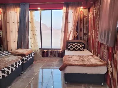 a bedroom with two beds and a large window at Nafa Rum Camp in Wadi Rum