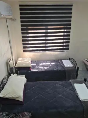 two beds in a room with a window with blinds at hostel ـ Karak dream in Kerak