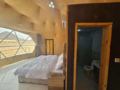 a bedroom with a bed and a bathroom with a window at Salma Desert Camp in Wadi Rum