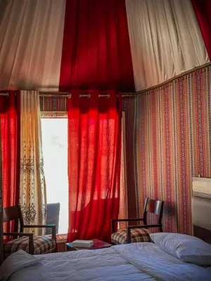 a bedroom with red curtains and two beds and a window at Tower Rum Camb in Wadi Rum