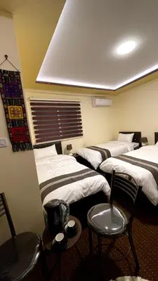 a room with four beds and chairs and a window at Ad Deir Guesthouse in Wadi Musa