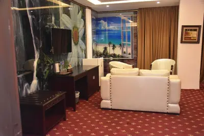 a living room with white chairs and a television at Madison Hotel in Amman