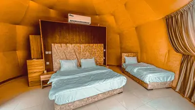 two beds in a bedroom with an orange wall at Mahmmad Luxury Camp in Wadi Rum