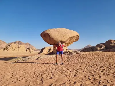 a woman holding up a large rock in the desert at Mahmmad Luxury Camp in Wadi Rum