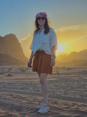 a woman standing in the desert with the sunset in the background at Mahmmad Luxury Camp in Wadi Rum
