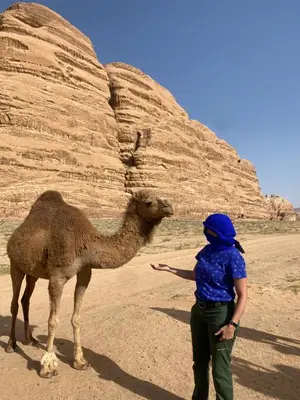 a woman standing next to a camel in the desert at Wadi Rum Cream in Wadi Rum