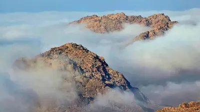 a mountain in the sky with a bunch of clouds at Petra Wow Hostel in Wadi Musa