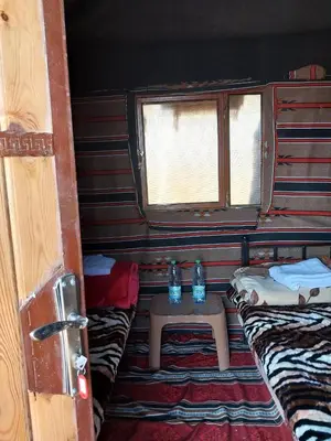 a room with two beds and a table and a window at Feynan wild camp in Al Khuraybah