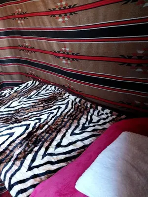 a close up of a bed with a zebra print blanket at Feynan wild camp in Al Khuraybah