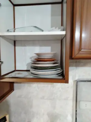 a stack of plates in a cabinet in a kitchen at شقه مفروشة الجبيهه in Amman