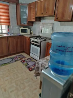 a kitchen with wooden cabinets and a stove top oven at شقه مفروشة الجبيهه in Amman