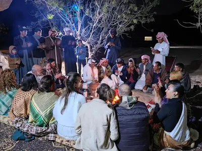 a group of people sitting around a circle with a fire at Namla Bedouin Camp in Umm Şawwānah