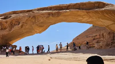 a group of people walking under an arch in the desert at Rum Darien Camp in Wadi Rum