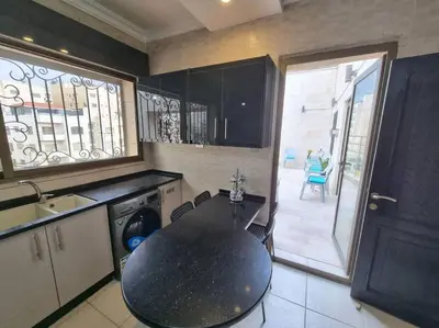 a kitchen with a black table and a sink and a table at Deir Ghbar 3 rooms apart in Amman