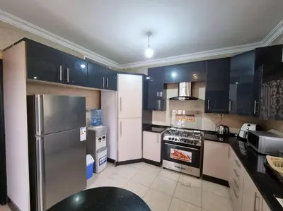 a kitchen with black and white cabinets and appliances at Deir Ghbar 3 rooms apart in Amman