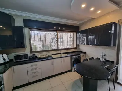 a kitchen with a table and a window in it at Deir Ghbar 3 rooms apart in Amman