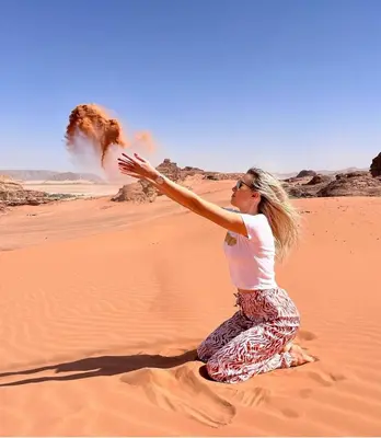 a woman sitting on the sand in the desert at Wade rum natural in Wadi Rum