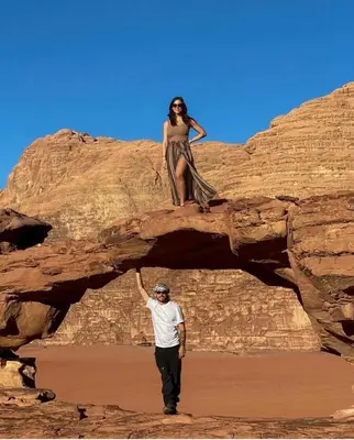 a man standing on a rock with a woman on it at Wade rum natural in Wadi Rum