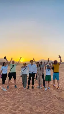a group of people standing in the desert with their hands in the air at Wade rum natural in Wadi Rum