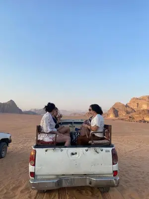 three women sitting in the back of a truck in the desert at Yara camp in Wadi Rum