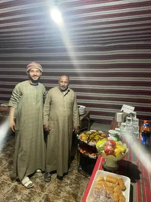 two men standing next to a table with food at Yara camp in Wadi Rum