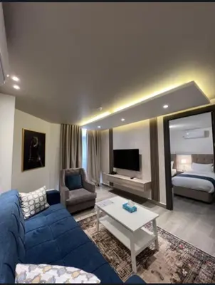 a living room with a blue couch and a bed at Red Carpet Hotel & Suites in Amman