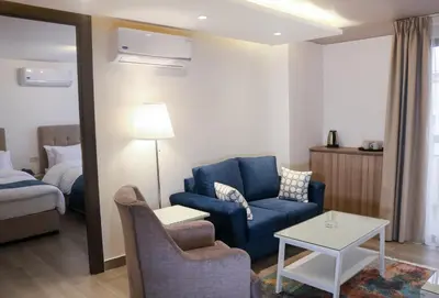a living room with a blue couch and a bed at Red Carpet Hotel & Suites in Amman
