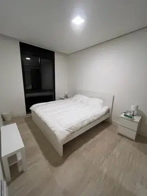 a white bedroom with a bed and a table at Ayla and chill Restricted to families and couples only in Aqaba