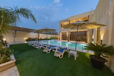 a pool with chairs and umbrellas next to a building at Adam's Luxury Villa DeadSea in Sowayma