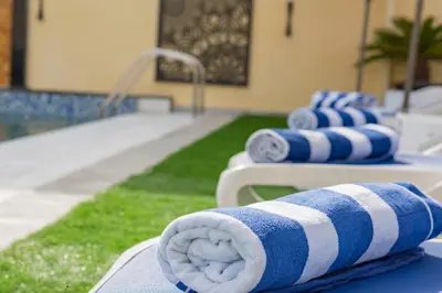 a row of towels sitting on beds next to a pool at Adam's Luxury Villa DeadSea in Sowayma