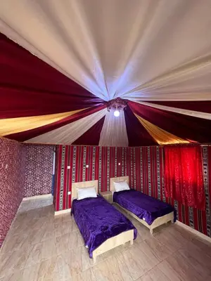 two beds in a room with a tent at Al-Shakriya Village Camp in Wadi Rum