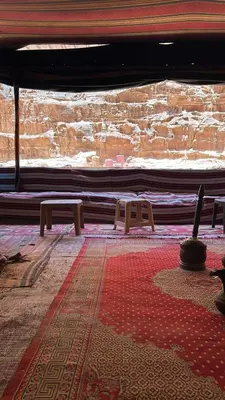 a room with two benches and a stone wall at Whispering Rum in Wadi Rum