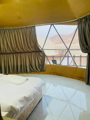 a bedroom with a bed and a large window at Whispering Rum in Wadi Rum