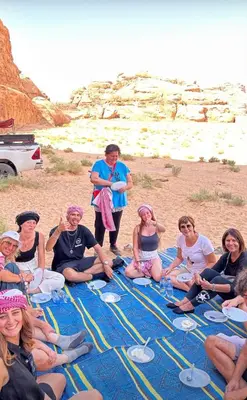 a group of people sitting on a blanket on the beach at Rayyan Bedouin life camp in Wadi Rum