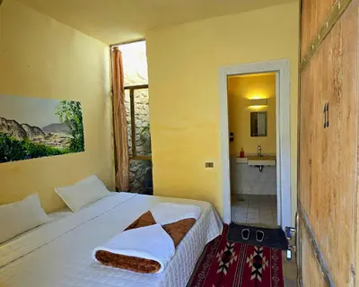 a bedroom with a bed and a bathroom with a sink at Dana Sunset Village Hotel in Dana